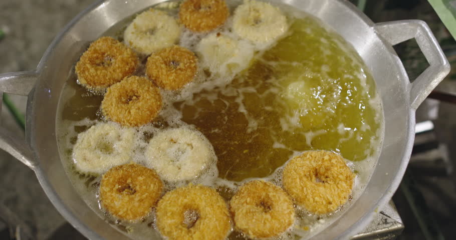 Tod Mun Goong shrimp donuts frying in hot oil on Thai street market crispy exotic snack with high calories trans fats sugar popular fast food in Southeast Asian urban culinary culture