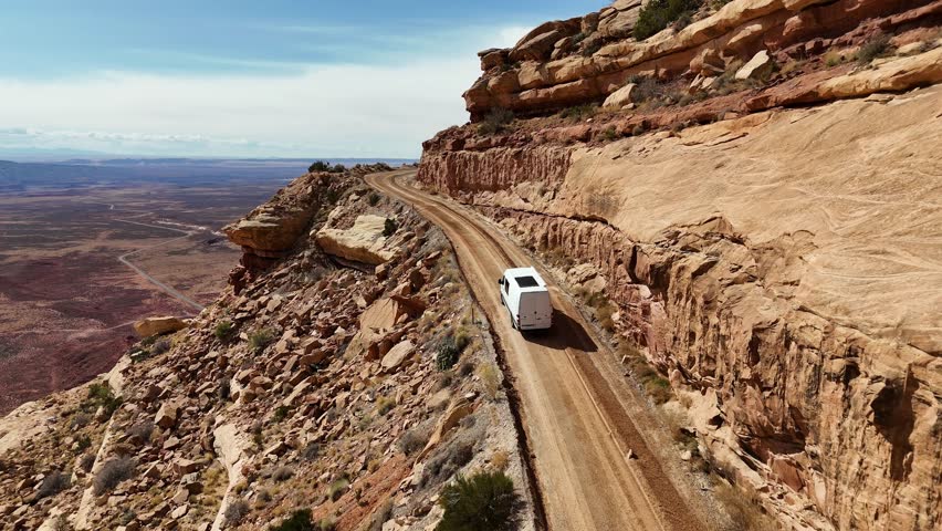 Camper Van Driving on the edge of a cliff going up a mountain, The Moki Dugway near Mexican Hat, Utah, Drone View