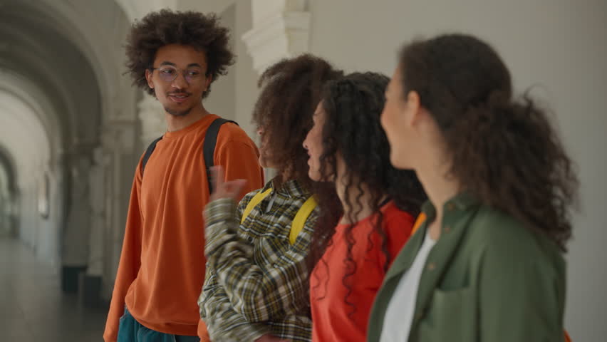 Group happy diversity students in university corridor talking smiling laughing four multiracial friends in college African American man guy with Arabian Hispanic women girls looking to camera positive