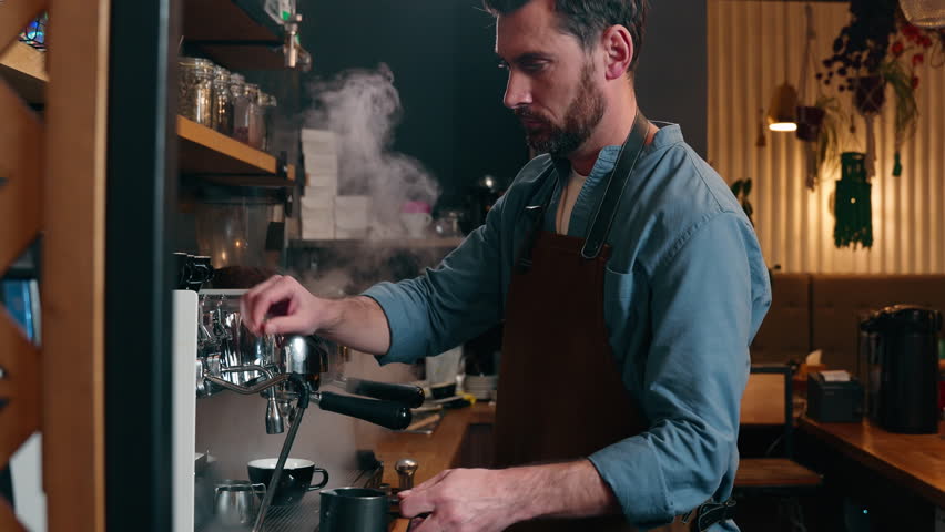 Adult Caucasian small business owner worker waiter barista male prepare order cafeteria catering guy man bartender pour hot espresso stream in mug coffee machine equipment in cafe employee make drink