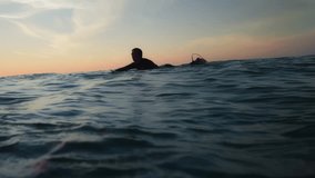 Surfers paddling through warm ocean waters at sunset, silhouettes against bright light. Calm waves, friendly vibe, and scenic horizon for a relaxed coastal session in Hossegor - Powered by Shutterstock - Get 15% off with code: PIKWIZARD15