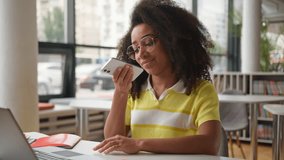 African American woman female student girl in school university college with laptop e-learning studying online prepare exams record audio message voice dictate on mobile phone searching vocal command - Powered by Shutterstock - Get 15% off with code: PIKWIZARD15