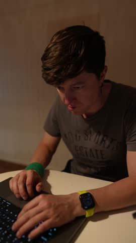 A Focused Young Man Working Diligently on His Laptop Late at Night with Determination and Intensity