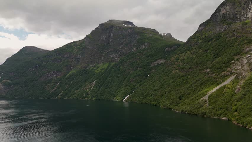 Discover spectacular vistas of Norway Geiranger fjords, where towering mountains meet calm waters. Experience the lush greenery and the natural beauty that defines this iconic landscape.
