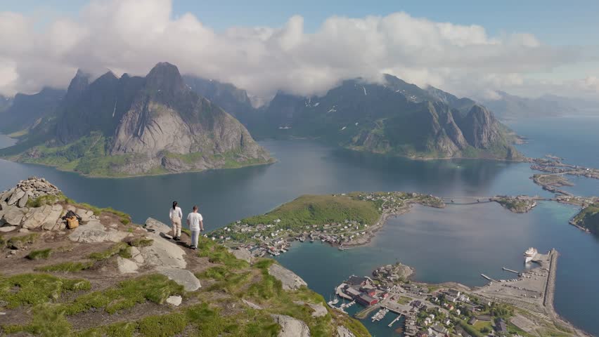 Visitors marvel at stunning views from a mountain peak in Lofoten Norway, overlooking serene fjords and picturesque villages. The enchanting scenery captures the essence of natures beauty 