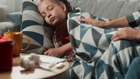 Caucasian family at home ill sick sleeping little girl child kid daughter suffering disease flu caring mother woman female measure fever forehead with hand cover baby with blanket health medicine - Powered by Shutterstock - Get 15% off with code: PIKWIZARD15