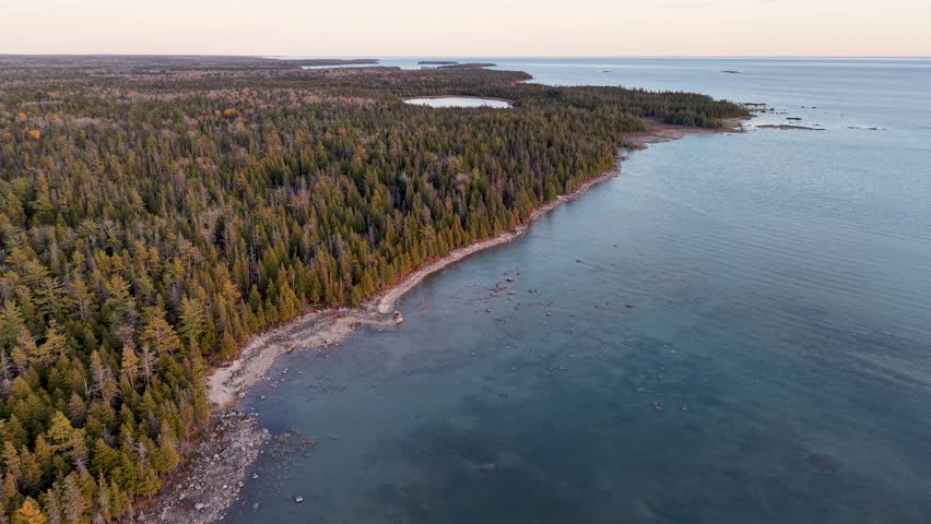 Drone flight over a forested peninsula on Lake Superior’s coastline in Michigan’s Upper Peninsula during golden hour