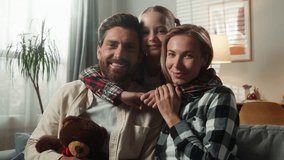Portrait happy smiling healthy family at home looking at camera smile together at own apartment insurance bank medicine parents on couch with little daughter child kid baby girl hugging cuddling love - Powered by Shutterstock - Get 15% off with code: PIKWIZARD15