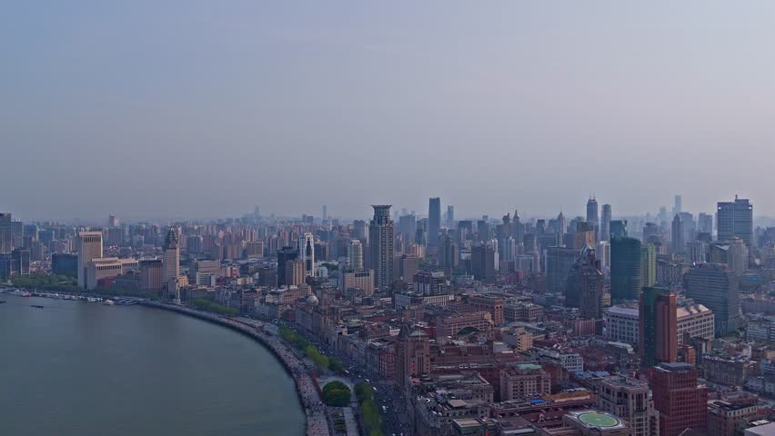 Shanghai, China - April 8th 2025: 4K real time Aerial view of Shanghai skyline and winding river at sunset.