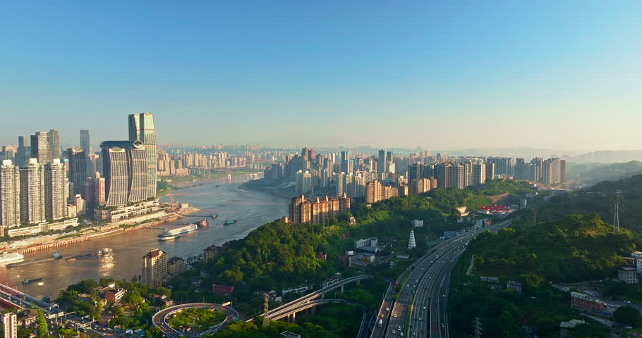 Aerial view overlooking the modern Chongqing cityscape with skyscraper complex beside the river and highway.
