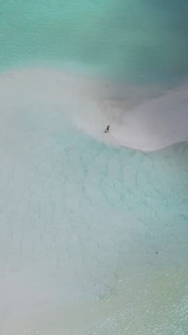 Drone point of view of lonely caucasian male tourist walking on tropical white sandbank near Thulusdhoo island.Stunning landscape with tropical beach and turquoise water of Indian Ocean.Maldives