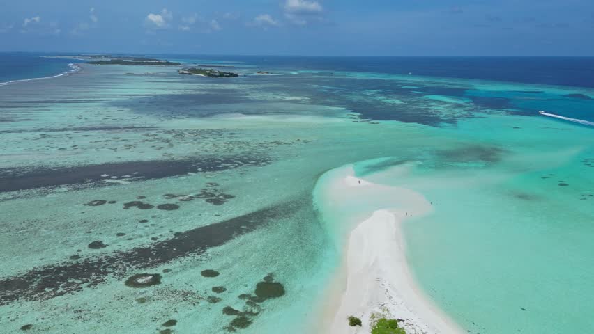 Aerial view of Thulusdhoo island.Maldives.Beautiful white sand beach long sandbar.The white sand beach is surrounded by turquoise water of Indian Ocean.People walking on the beach