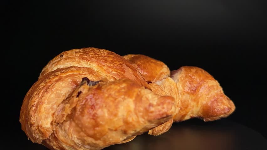 Croissant with wild berry jam rotates in a smooth half-turn on black background. Ideal for culinary content, bakery ads, breakfast themes, pastry or cookie-related food promos.