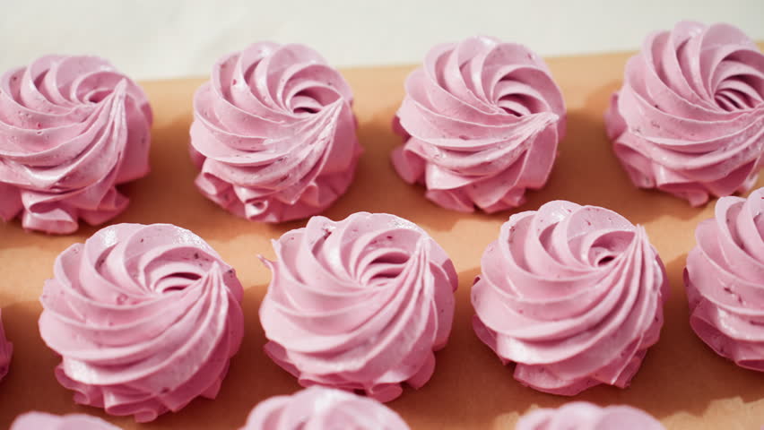 Close up of neatly displayed swirl pink cupcakes on brown baking paper, showing smooth frosting texture and uniform shapes, perfect for dessert presentation