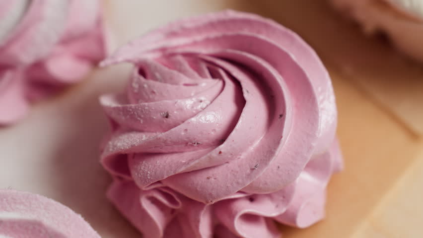 Extreme close up of sugar being gently sprinkled on swirl pink cupcake showcasing fine texture of frosting and sugar granules, highlighting dessert elegant detail and pastel color