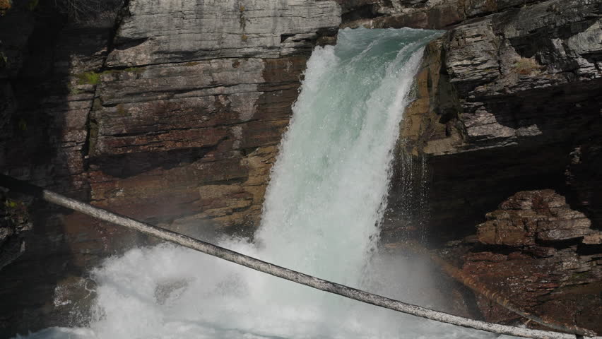 Powerful waterfall rushes through rocky cliffs at St Mary Falls, Montana, USA