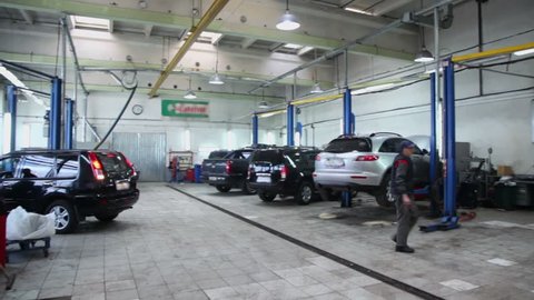 Man walks in car service center with many cars, panoramic motion