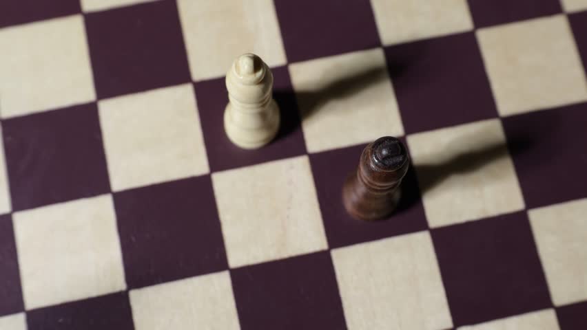 Shot from above a chessboard with two kings, moving with shadows.