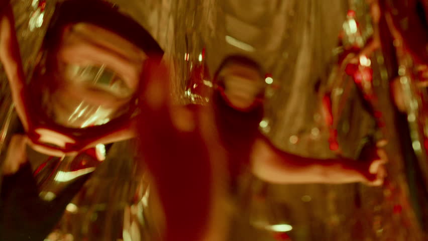 Young woman expressing emotions through moves, giving ethereal dance performance surrounded by surreal distorted reflections under colorful neon illumination