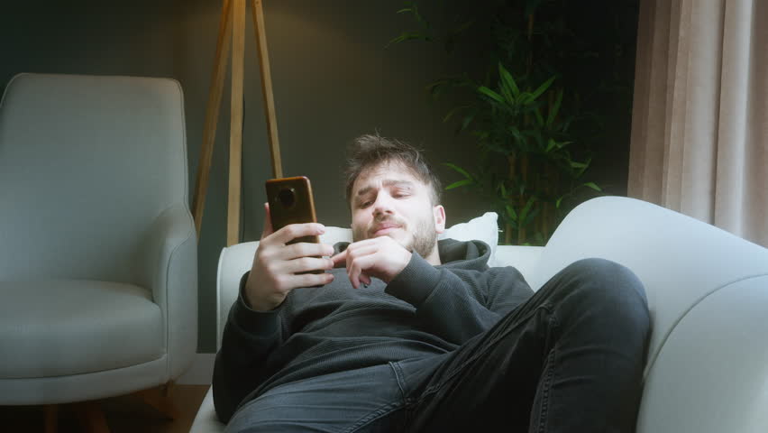 Frustrated Young Man Exhausted from Watching Short Videos on Phone, Feeling Wasted Time