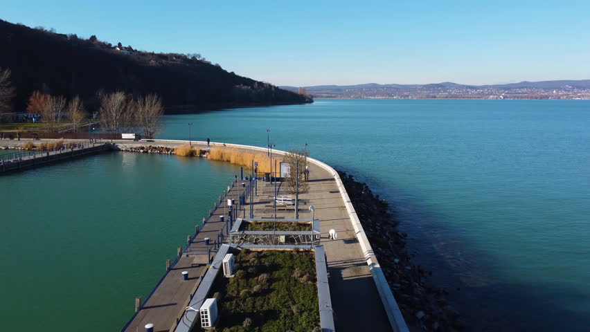 Top down flyover of Tihany ferry waiting zone, neat benches arranged beside dock