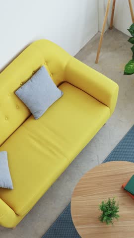 Professional woman working from home opening laptop while sitting on yellow couch