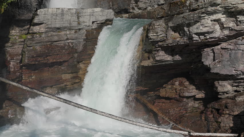 Waterfall crashing between layered rocks in St Mary Falls, Montana, USA