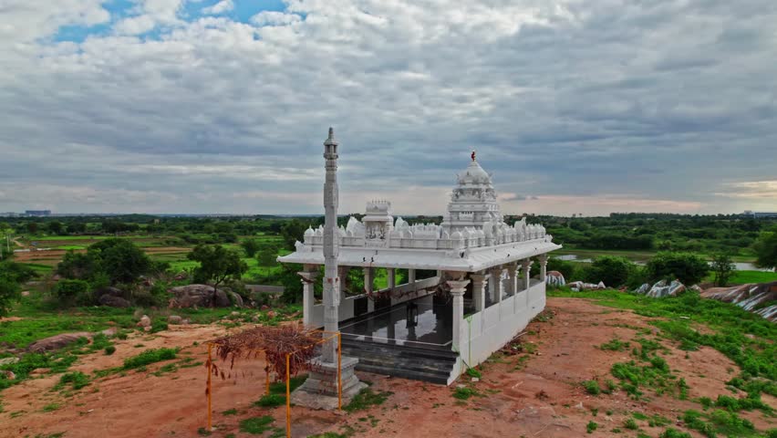 Temple with Dhwaja Stambha and agricultural land at day time, overtake shot or push in shot, drone shot, 4k.