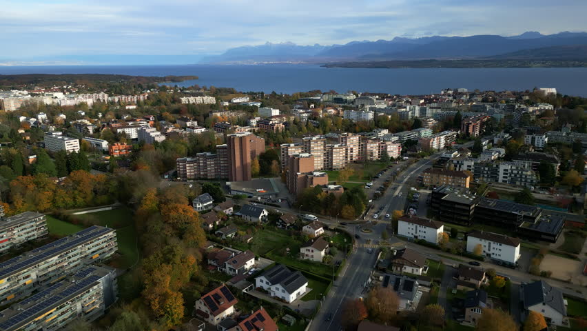 Push in drone shot of Levratte district with cityscape, lake Geneva and mountain during the day in Nyon, canton of Vaud, Switzerland