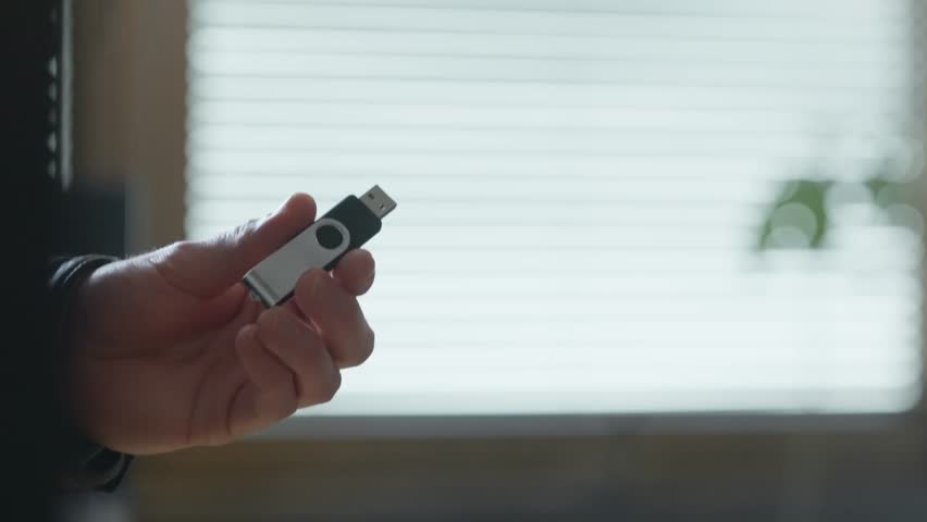 USB flash drive being handed from one person to another in a secret exchange. Close-up. Digital data transfer, confidential information, espionage, hacking, cybersecurity, intelligence, or spy word