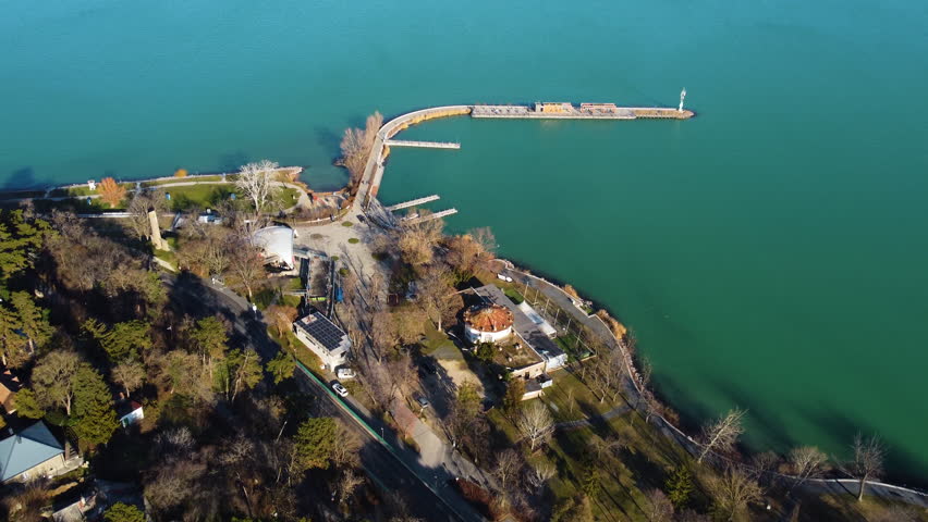 Top down aerial of ferry dock stretching into green lake waters near Tihany, Hungary