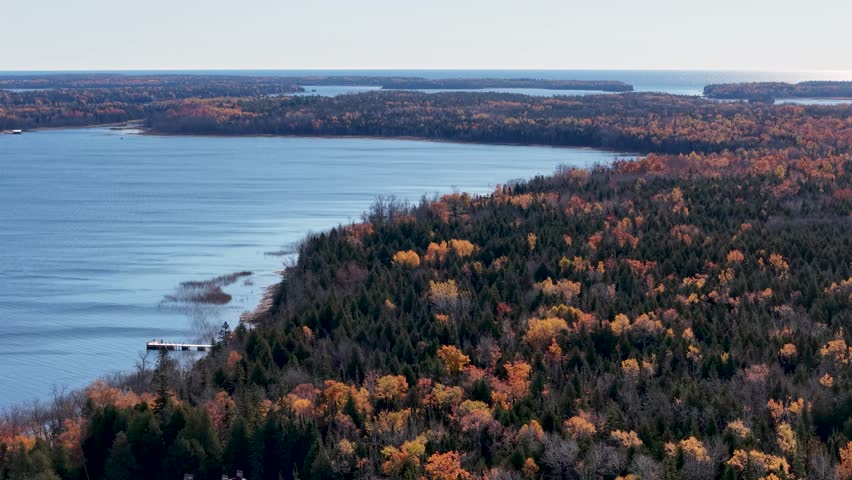 Expansive drone shot of vibrant autumn foliage along a rugged Lake Superior shoreline in Michigan’s Upper Peninsula