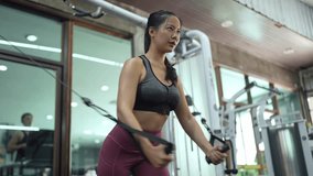 Focused asian sportswoman executing cable fly exercise with precision on weight training machine, demonstrating strength and dedication within modern fitness center environment - Powered by Shutterstock - Get 15% off with code: PIKWIZARD15