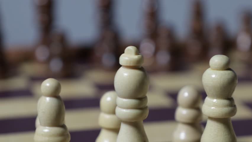 Moving shot close up of chess pieces on a chessboard.