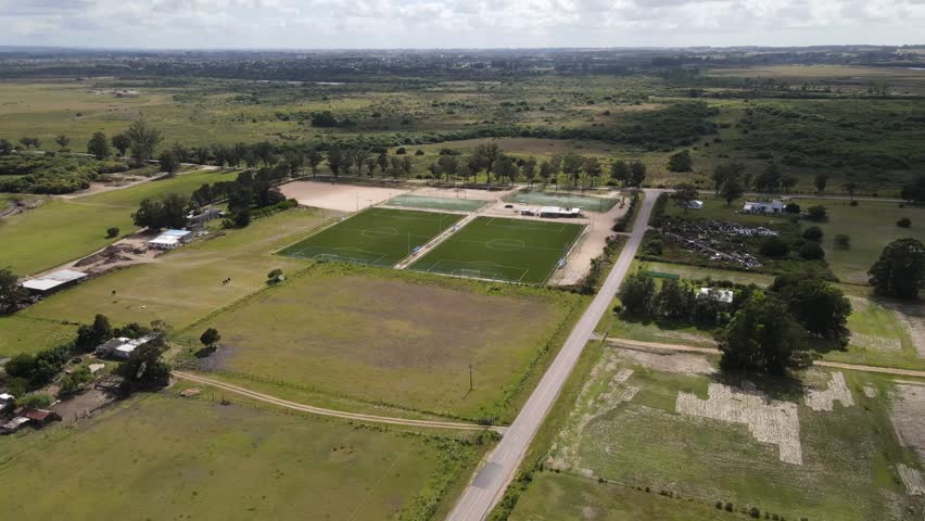 Construction progress of soccer fields emerging in rural landscape, aerial perspective revealing green terrain transformation and infrastructure development