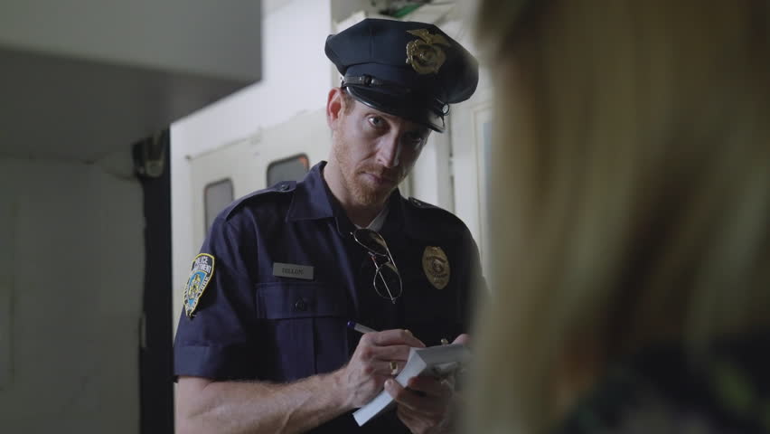 Police officer, investigator, or detective stands at a woman's front door, questioning her and writing notes in a small notebook. Witness statement, investigation, law enforcement, crime-solving, Cop.