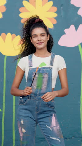 Happy woman, face and painter with confidence for art, design or colorful creativity at school. Portrait, female person or artist with smile, arms crossed or floral wall for mural activity or service