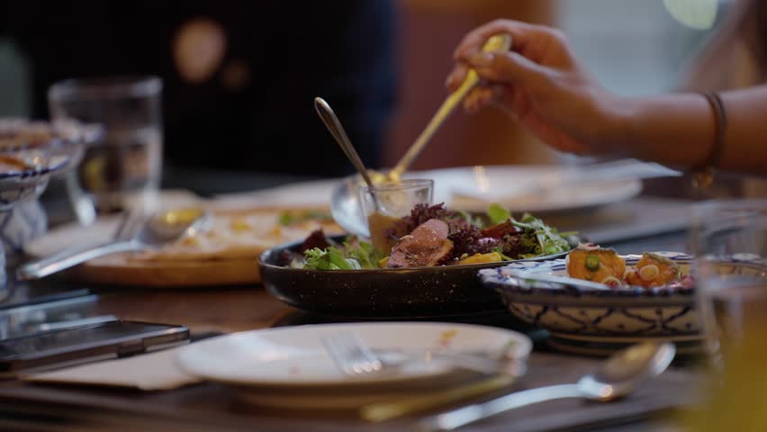 A hand serving fresh vegetable salad onto a plate from a buffet table at a banquet event. Cropped shot of a hand serving healthy salad on plate while having lunch in a restaurant