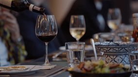 A waiter is pouring red wine into a glass on a dining table at a banquet event, Waiter pouring wine for customer at hotel restaurant. Exclusive dining event, sophisticated and celebratory - Powered by Shutterstock - Get 15% off with code: PIKWIZARD15