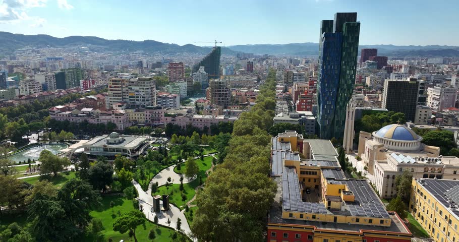Wide aerial panorama of Tirana city showing dense development and green park zones below