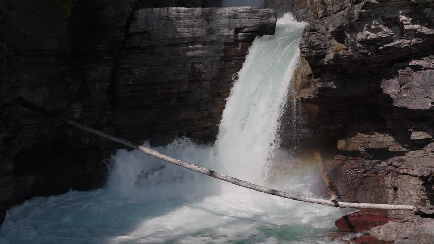 Water rushes down St. Mary Falls, framed by rugged cliffs in Montana, USA