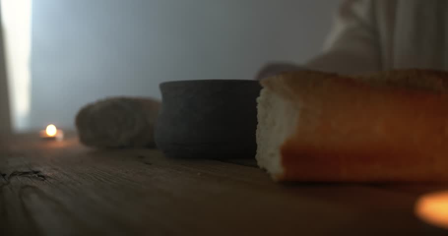 Jesus Christ with sacraments of bread and wine on a table as a representation of the last supper, communion. Perfect for Easter, sermon video, or worship background.