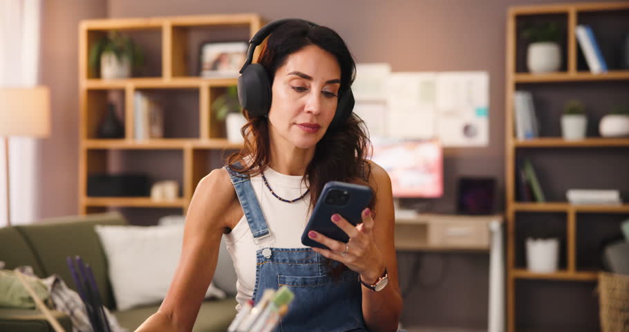 Coffee, artist and woman with phone for music or listening to inspiration podcast. Drink, headphones and painter on mobile for creative hobby, audio and streaming video for art design in home studio