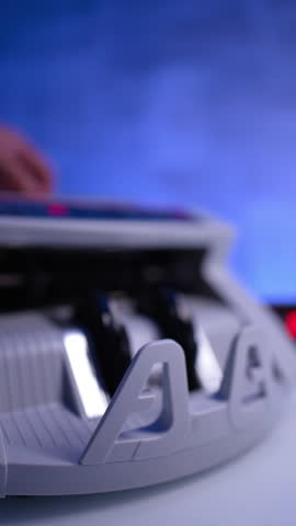 American money processed in cash counting machine. One hundred dollars fall on the device holder. Close up. Blurred image. Vertical video.