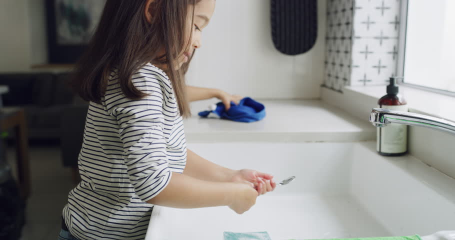 Sisters, kids and washing dishes in kitchen, cleaning or learning hygiene in home. Children, soap and spoon at sink for housework, chores and girls together to help wipe counter with cloth and sponge