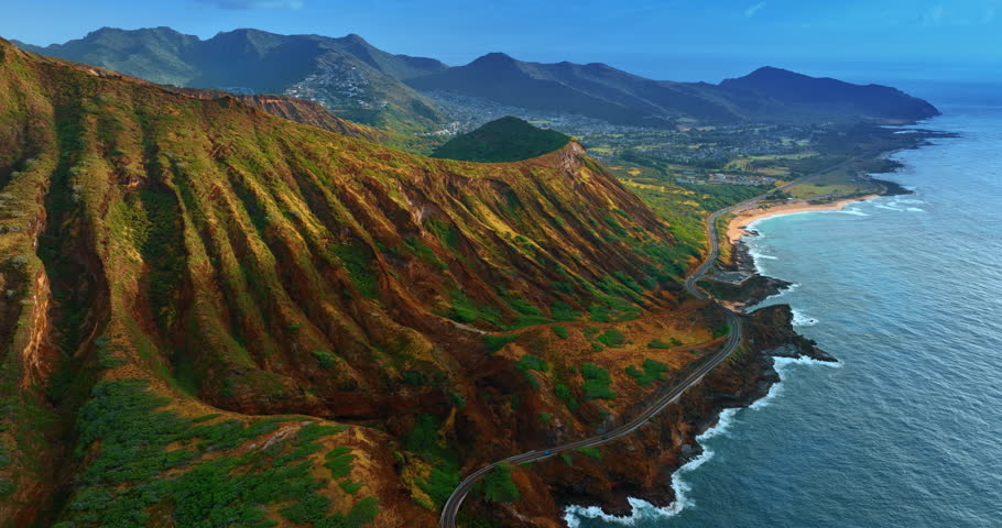 Breathtaking scenery of the mountainous shore of the Island Oahu, Hawaii, USA. Long highway stretches along the coast. Aerial perspective.