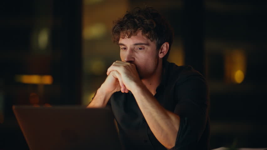 Stressed manager closing computer tired of overtime work closeup. Unmotivated employee finish late project worried deadline. Fatigued businessman thinking on financial crisis problem at dark workplace
