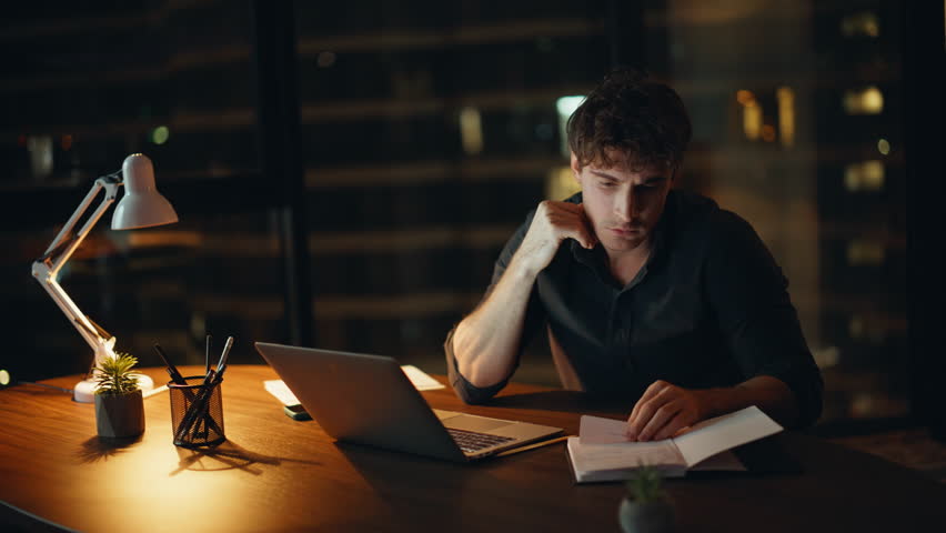 Shocked freelancer losing job reading laptop email at night home closeup. Desperate businessman receiving bad news at dark workplace under lamp light. Emotional entrepreneur worried money loss indoors