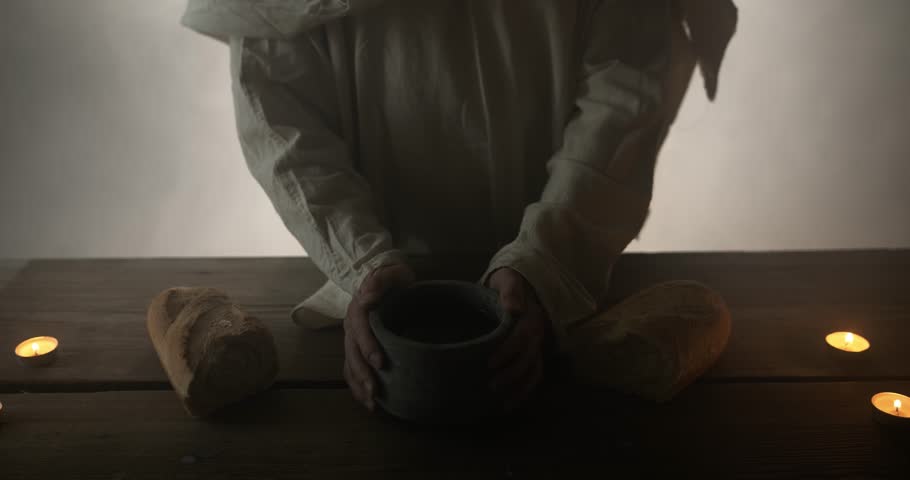 Jesus Christ in white robe and ambient, glowing light holding clay jar of wine as representation of the gospel, and the shed blood of Jesus on the cross. Easter Sunday visual.