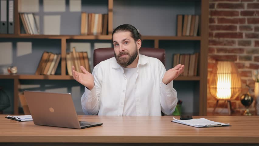 Playful Caucasian man raising shoulders with both palms up while smiling slightly. Shrugging and pretending innocence. Responding to mistake or avoiding responsibility during relaxed chat.